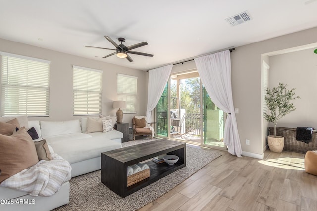 living room featuring light wood-type flooring, visible vents, ceiling fan, and baseboards