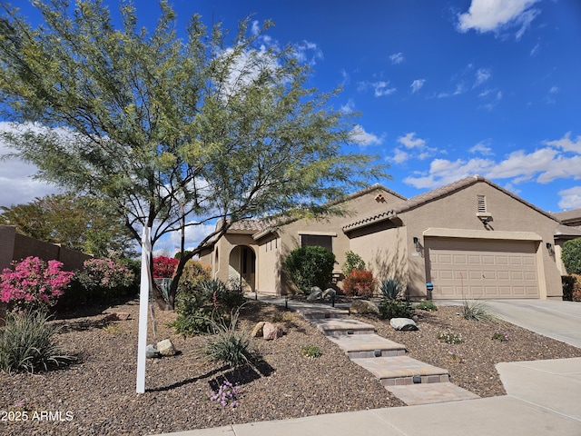 mediterranean / spanish-style home featuring a tile roof, stucco siding, concrete driveway, an attached garage, and fence