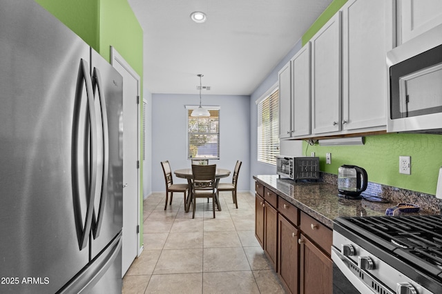 kitchen featuring light tile patterned flooring, appliances with stainless steel finishes, hanging light fixtures, a toaster, and visible vents