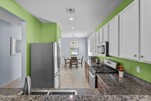 kitchen with white cabinets, stainless steel appliances, light tile patterned flooring, and visible vents