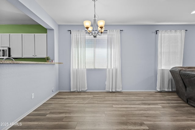 dining room with baseboards, a chandelier, and wood finished floors