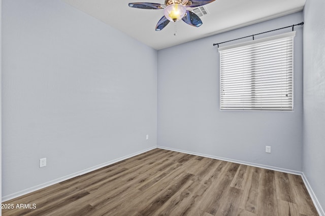 spare room with baseboards, ceiling fan, visible vents, and wood finished floors