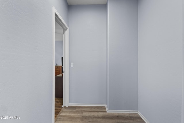 hallway featuring baseboards and wood finished floors