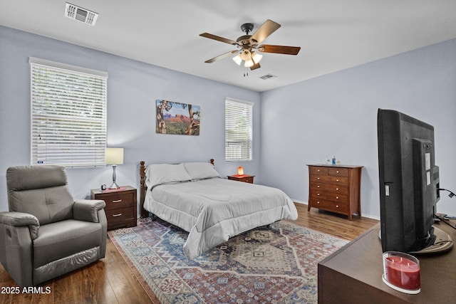 bedroom with a ceiling fan, visible vents, and wood finished floors
