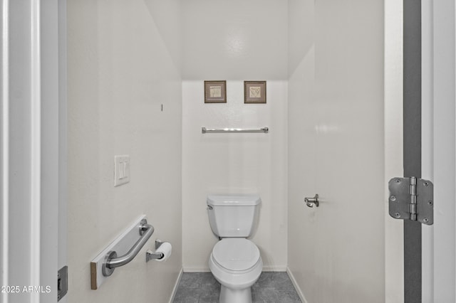 bathroom featuring baseboards, tile patterned flooring, and toilet
