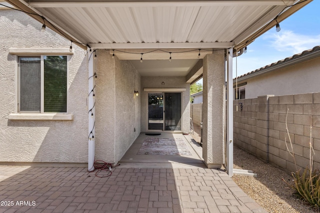 entrance to property featuring stucco siding and fence