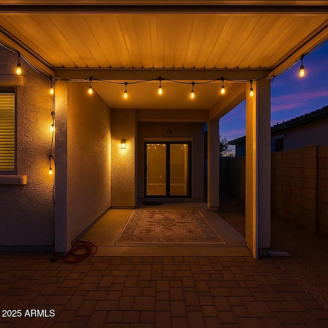 entrance to property with a patio, fence, and stucco siding