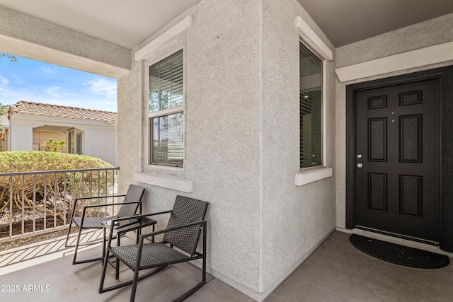 view of exterior entry featuring a porch and stucco siding