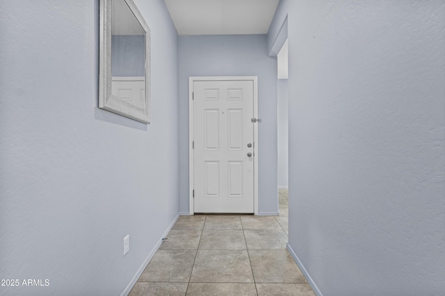 corridor featuring baseboards and light tile patterned flooring