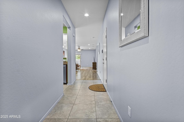 hallway with light tile patterned floors, baseboards, a textured wall, and recessed lighting
