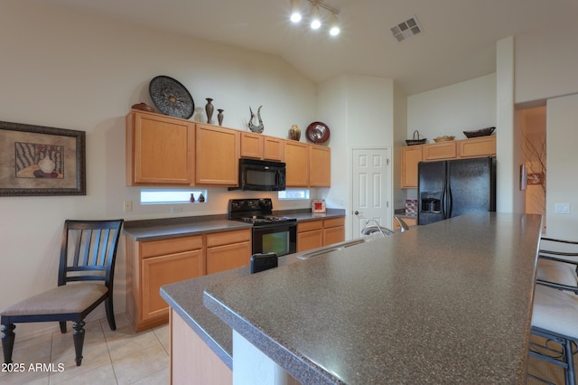 kitchen featuring sink, light tile patterned floors, light brown cabinetry, a kitchen island, and black appliances