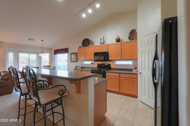 kitchen featuring hanging light fixtures, a kitchen breakfast bar, lofted ceiling, light tile patterned floors, and black appliances