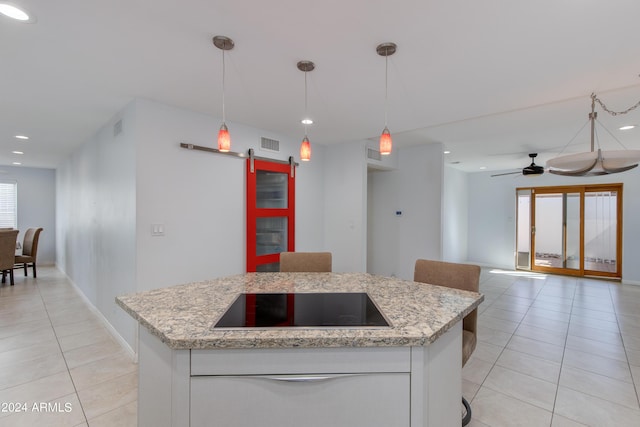 kitchen featuring light tile patterned floors, a barn door, white cabinetry, ceiling fan, and black electric cooktop