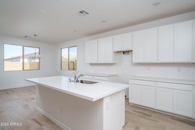 kitchen featuring pendant lighting, sink, white cabinetry, and a kitchen island with sink