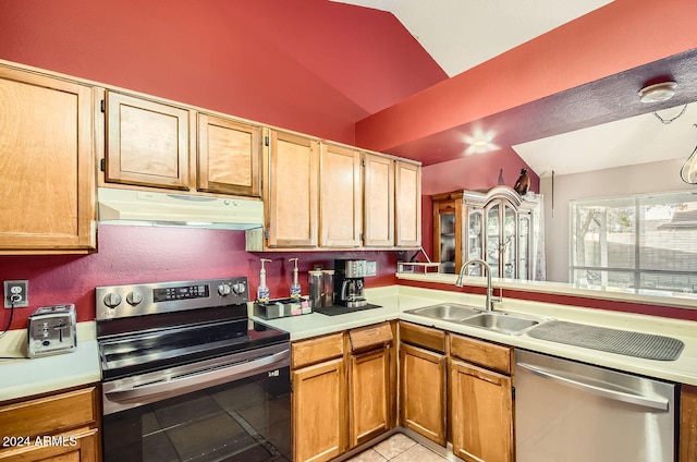 kitchen featuring sink, kitchen peninsula, vaulted ceiling, light tile patterned floors, and appliances with stainless steel finishes