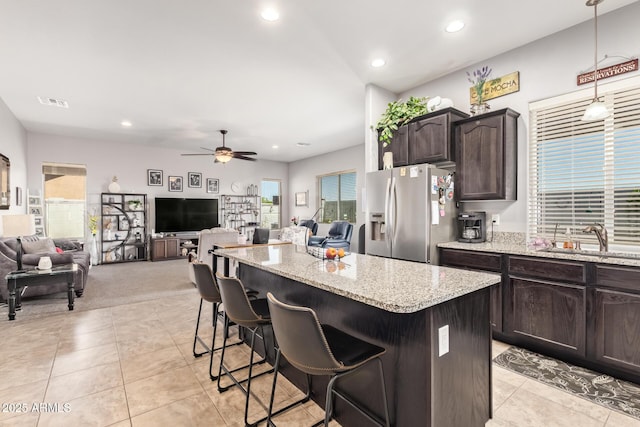 kitchen with a ceiling fan, a center island, a sink, open floor plan, and stainless steel fridge