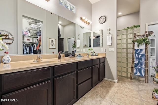 full bathroom with a sink, tile patterned flooring, double vanity, a towering ceiling, and a spacious closet