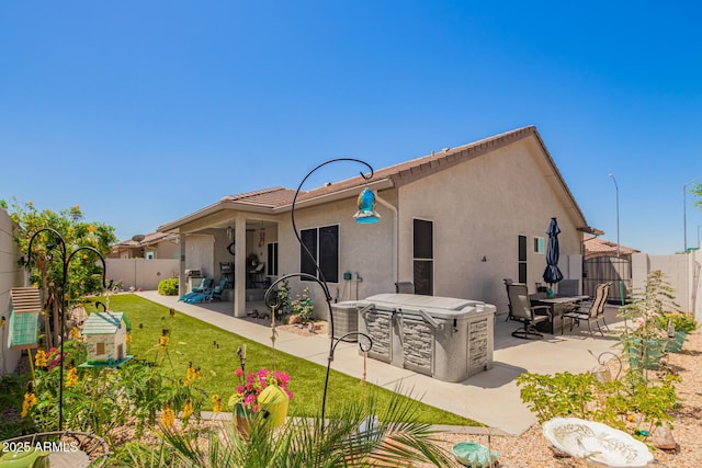 rear view of house with a fenced backyard, stucco siding, a yard, and a patio area
