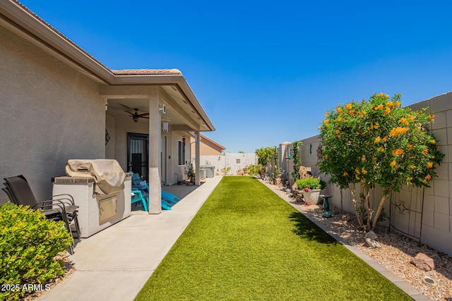 view of yard featuring ceiling fan and a fenced backyard