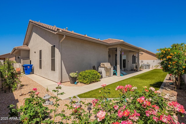 back of property with a patio, a fenced backyard, stucco siding, a ceiling fan, and a lawn