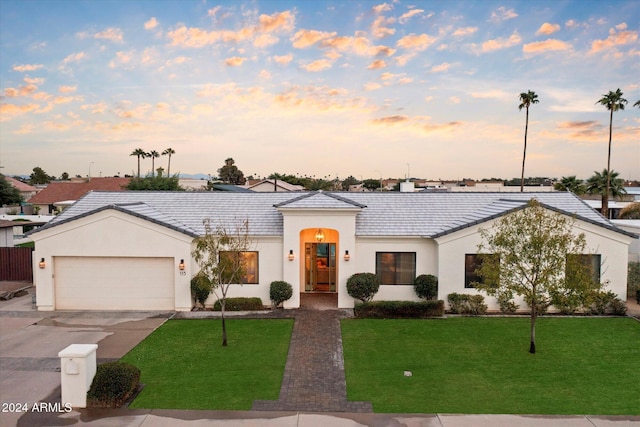 ranch-style house featuring a garage and a lawn