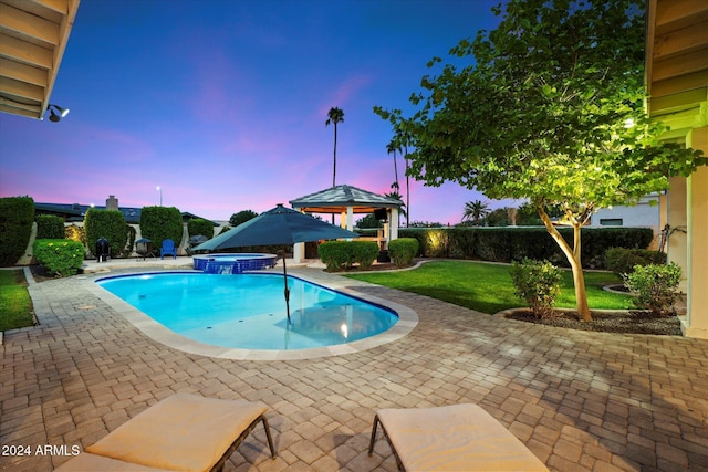 pool at dusk featuring a gazebo, a patio area, and an in ground hot tub