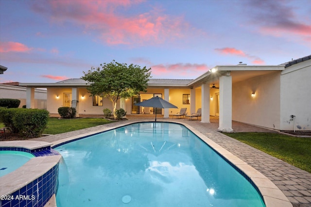 pool at dusk with a patio area and a yard