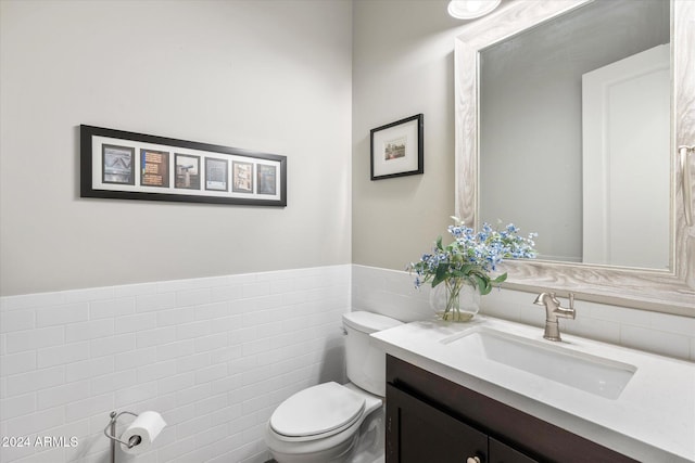 bathroom with vanity, toilet, and tile walls