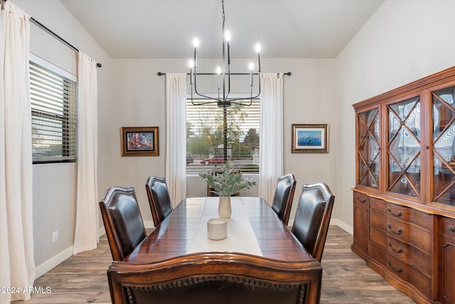 dining area featuring wood-type flooring and an inviting chandelier