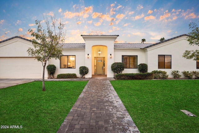 mediterranean / spanish home with a lawn and a garage