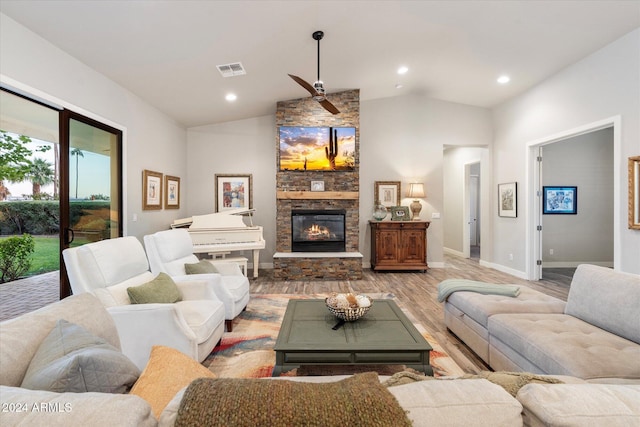 living room featuring a stone fireplace, ceiling fan, wood-type flooring, and vaulted ceiling