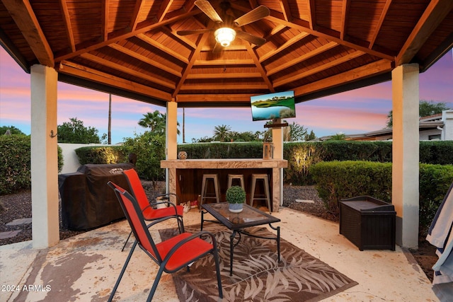 patio terrace at dusk featuring a gazebo, area for grilling, and ceiling fan