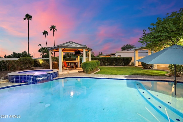 pool at dusk with a gazebo, an outdoor bar, an in ground hot tub, and a lawn