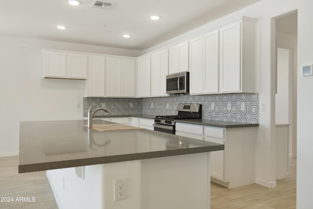 kitchen featuring light wood-type flooring, white cabinets, visible vents, appliances with stainless steel finishes, and backsplash