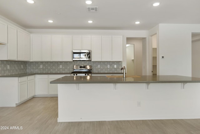 kitchen with white cabinetry, visible vents, a sink, dark countertops, and stainless steel appliances