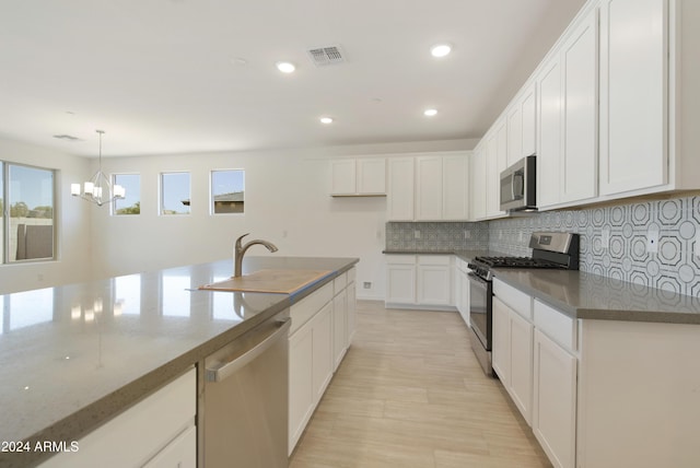 kitchen featuring a chandelier, white cabinets, visible vents, appliances with stainless steel finishes, and a sink