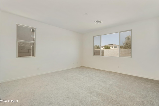 carpeted empty room featuring baseboards and visible vents