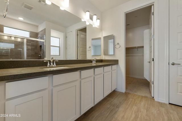 full bathroom featuring a sink, visible vents, a stall shower, and wood finished floors