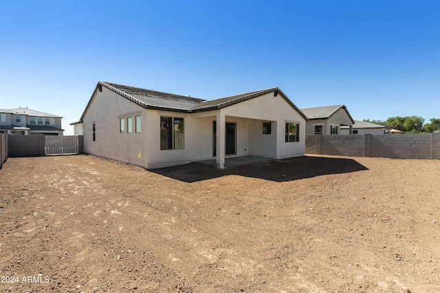 rear view of property with a patio area, stucco siding, a fenced backyard, and a tile roof