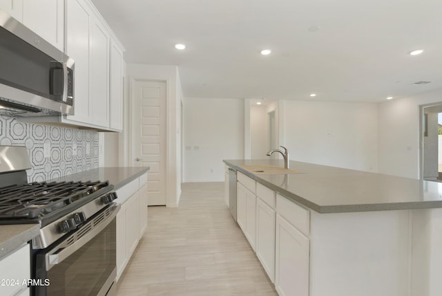 kitchen with a sink, an island with sink, recessed lighting, light wood finished floors, and stainless steel appliances