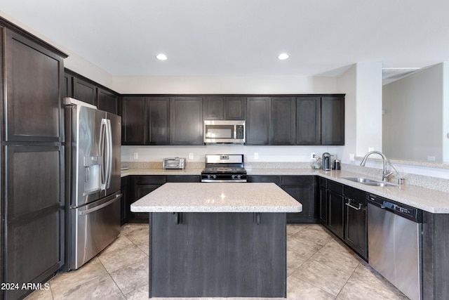 kitchen featuring light stone counters, kitchen peninsula, stainless steel appliances, dark brown cabinetry, and sink