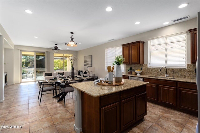 kitchen featuring decorative light fixtures, a kitchen island, plenty of natural light, and sink