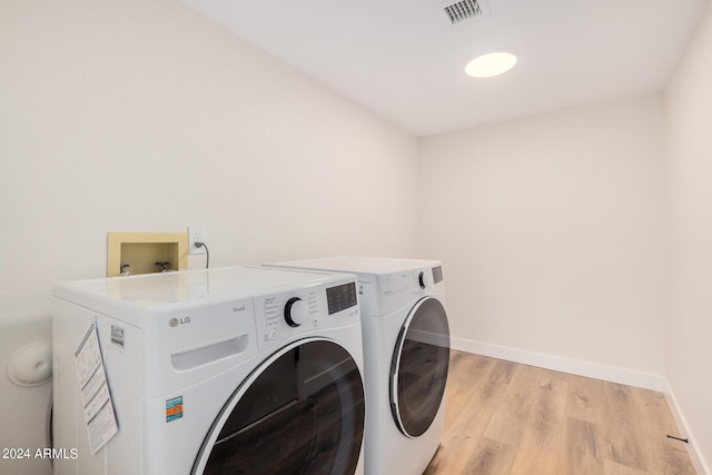 laundry room with washer and dryer and light hardwood / wood-style floors