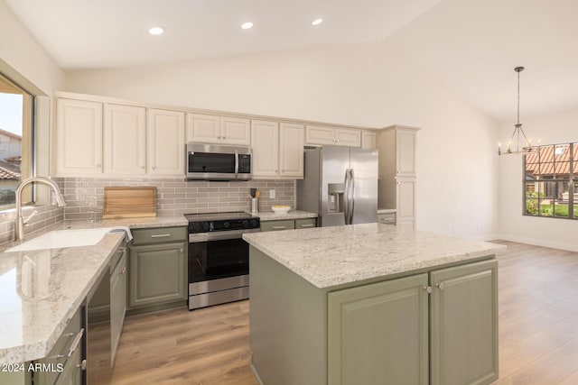 kitchen with sink, light wood-type flooring, decorative light fixtures, a kitchen island, and stainless steel appliances