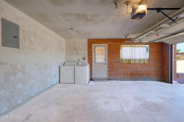 garage featuring electric panel, a garage door opener, and washing machine and clothes dryer