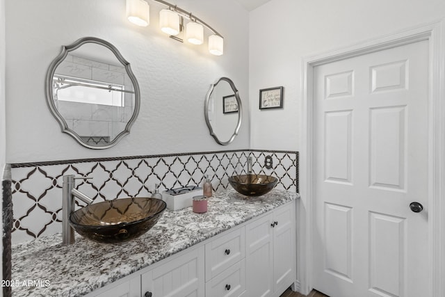 full bathroom with a sink, backsplash, and double vanity