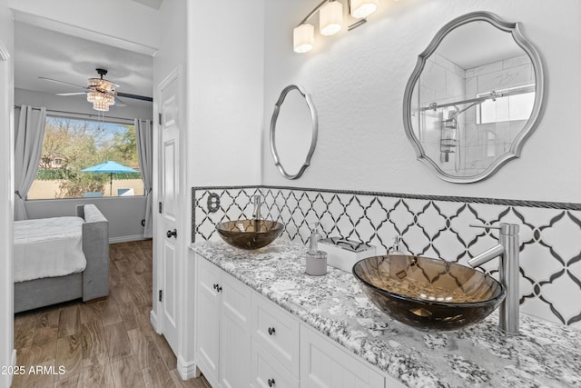 full bathroom with double vanity, a sink, decorative backsplash, and wood finished floors