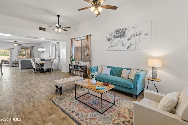 living room with a chandelier, wood finished floors, visible vents, and baseboards