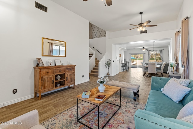 living area featuring ceiling fan, stairs, baseboards, and wood finished floors