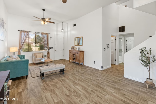 living area with visible vents, high vaulted ceiling, and light wood-style flooring